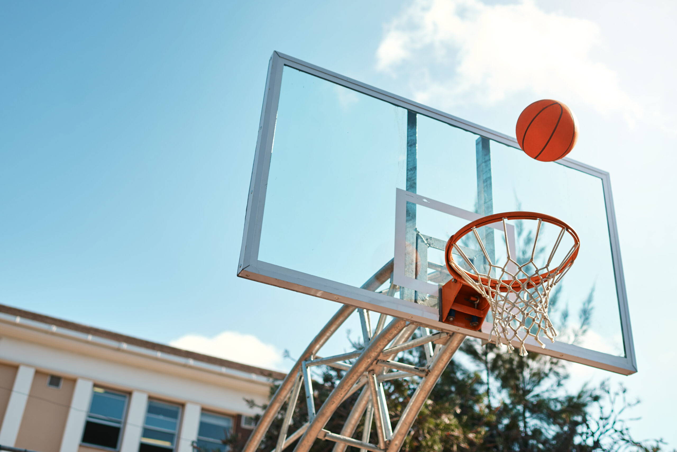 Still life shot of a basketball landing into a net on a sports court.