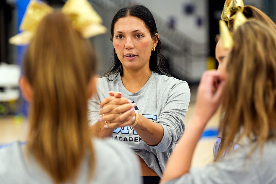 A DME cheer coach demonstrating hand placement to athletes during instruction.
