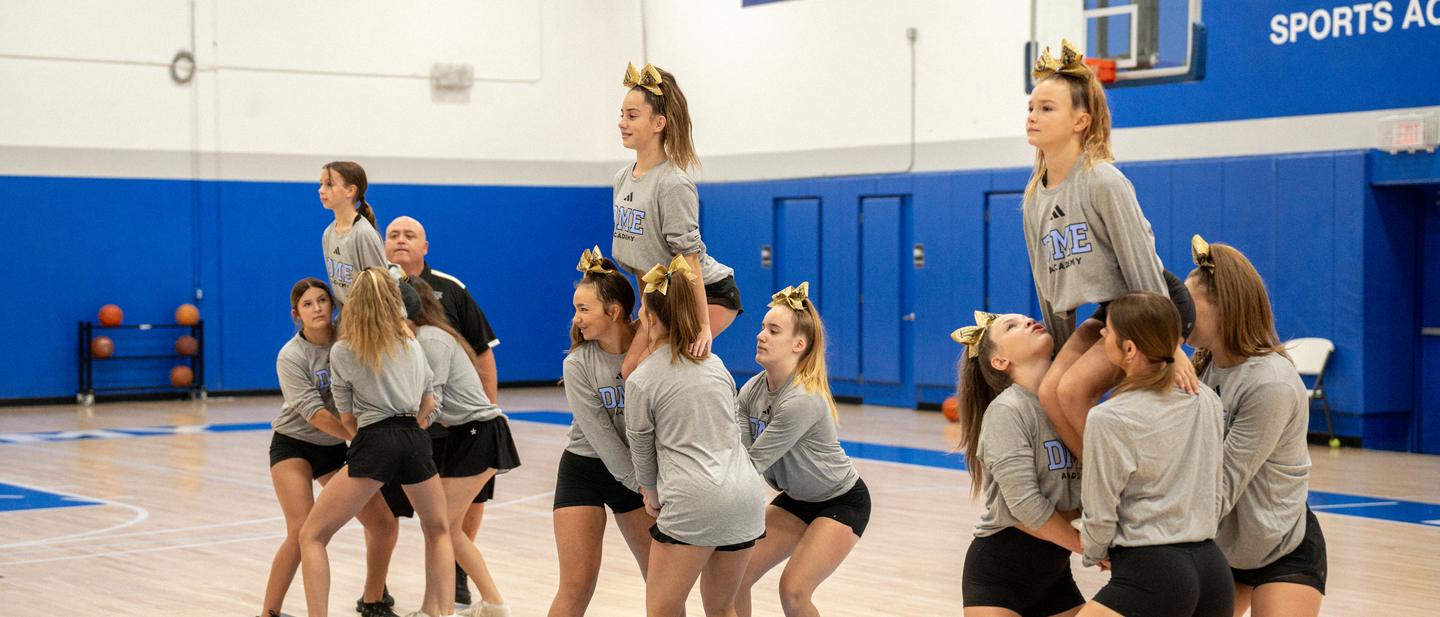 DME cheer athletes stretching together along the gym floor before a session.